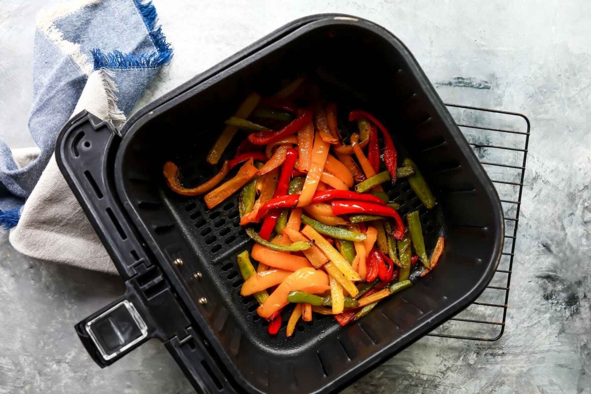 An air fryer basket with air fryer peppers in it.