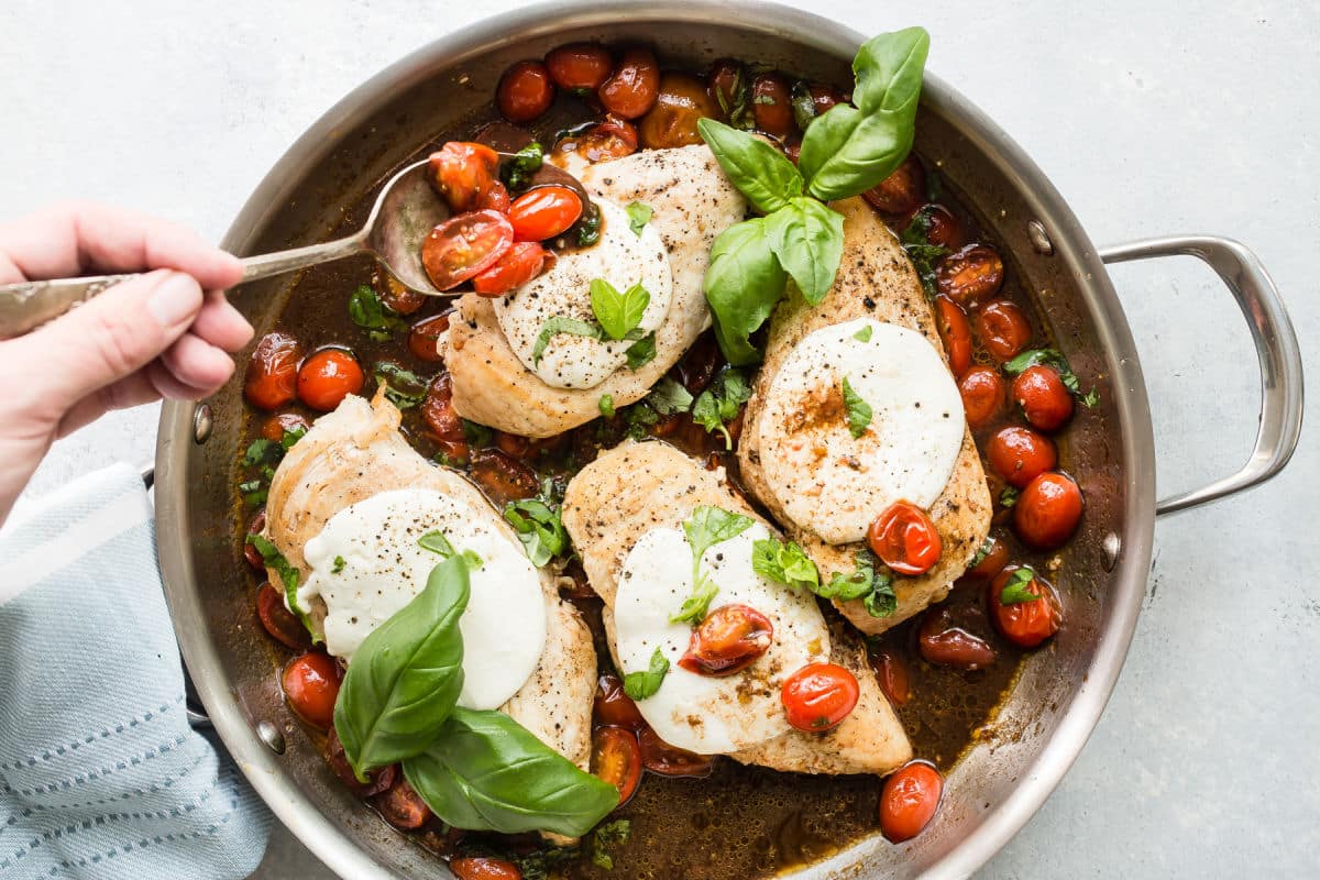 Caprese chicken in a stainless steel skillet.