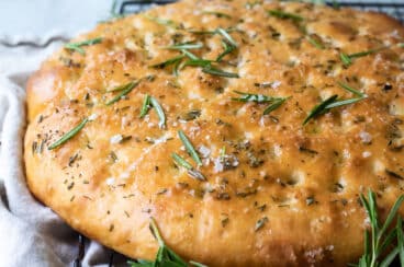 A loaf of focaccia on a cooling rack.
