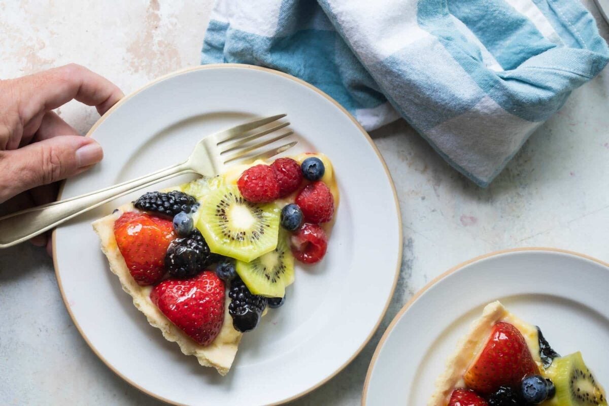 A slice of fresh fruit tart on a white plate.