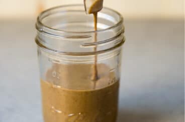 Tahini being poured into a mason jar.