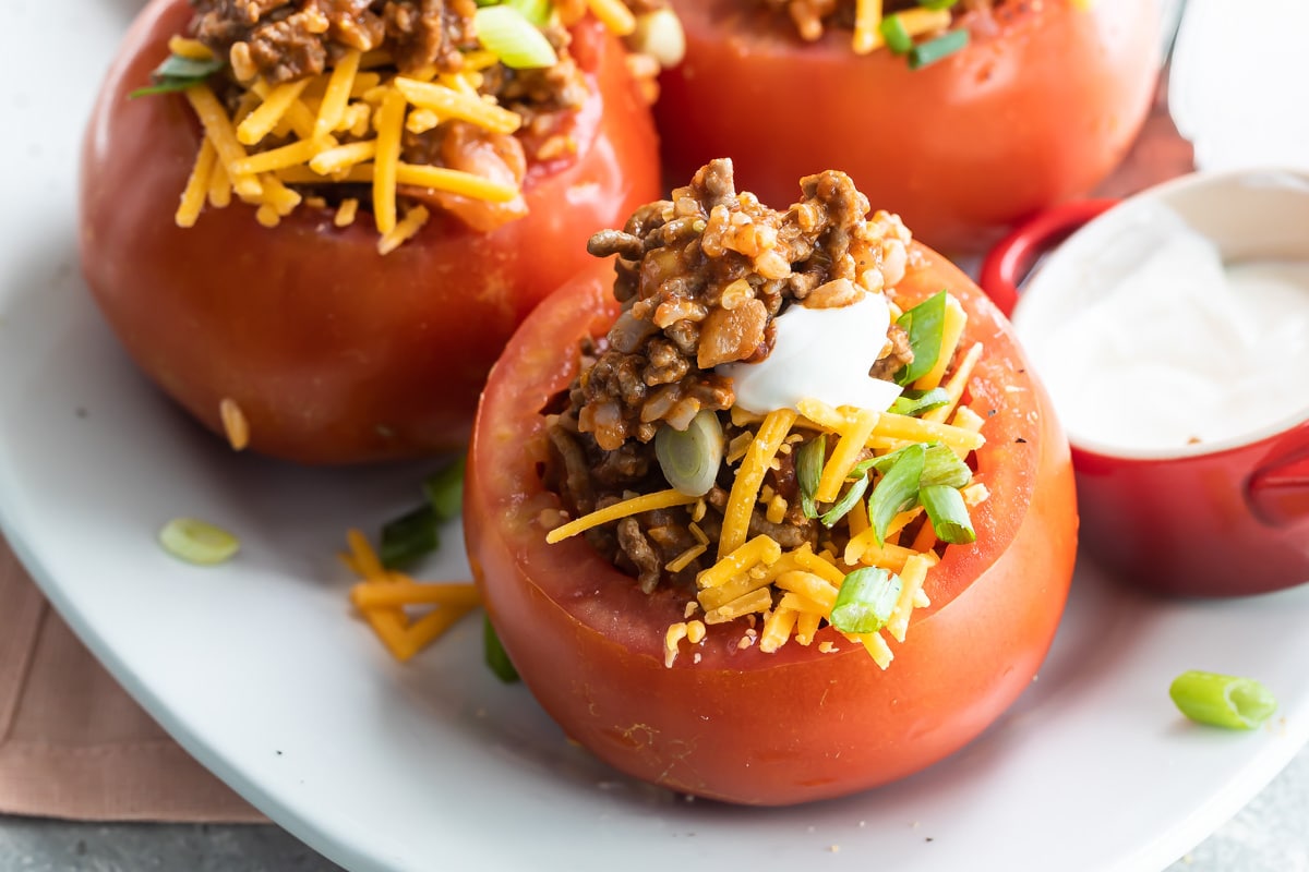 Taco stuffed tomatoes on a white platter.