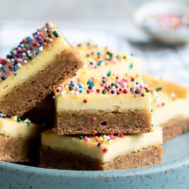 Sugar cookie cheesecake squares on a small blue plate.